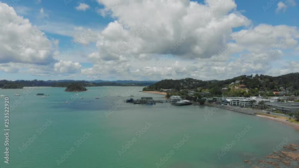 Fishing, sailing and diving destination Bay of Islands, New Zealand. Aerial view from drone pulling back to reveal the city on the shore of turquoise water and tiny tree covered islands. Fishing, sailing and diving destination Bay of Islands, New Zealand. Aerial view from drone pulling back to reveal the city on the shore of turquoise water and tiny tree covered islands.