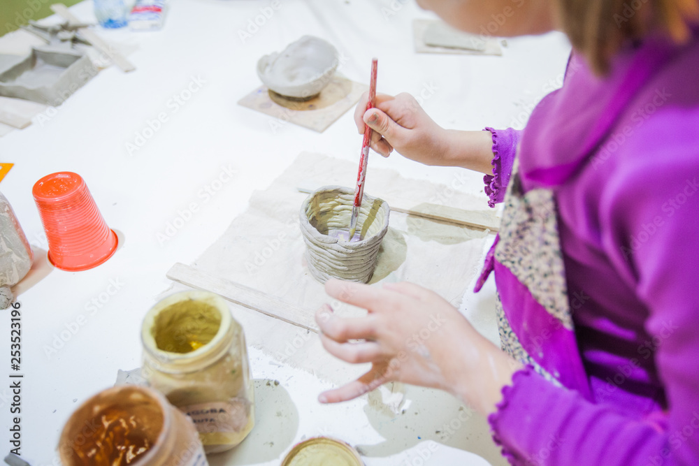 childrens hands painting with brush self-made clay items childrens hands painting with brush self-made clay items