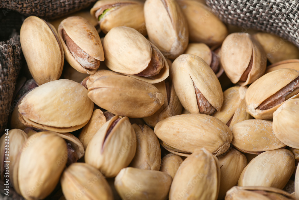 Roasted pistachios  in gray bag on textured  dark wooden background, top view. Copy space. 