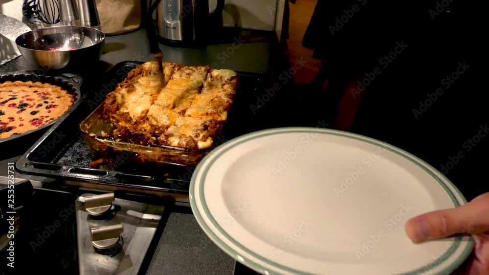 Serving Hot Lasagna from the dish to the plate with steam rising. Serving Hot Lasagna from the dish to the plate with steam rising.
