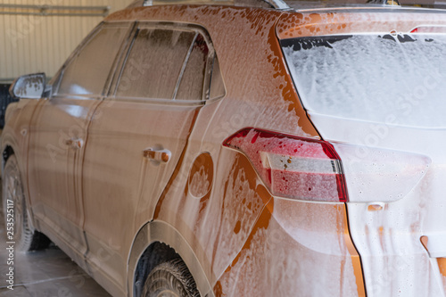 Car washing at car wash station with brush and foam.
