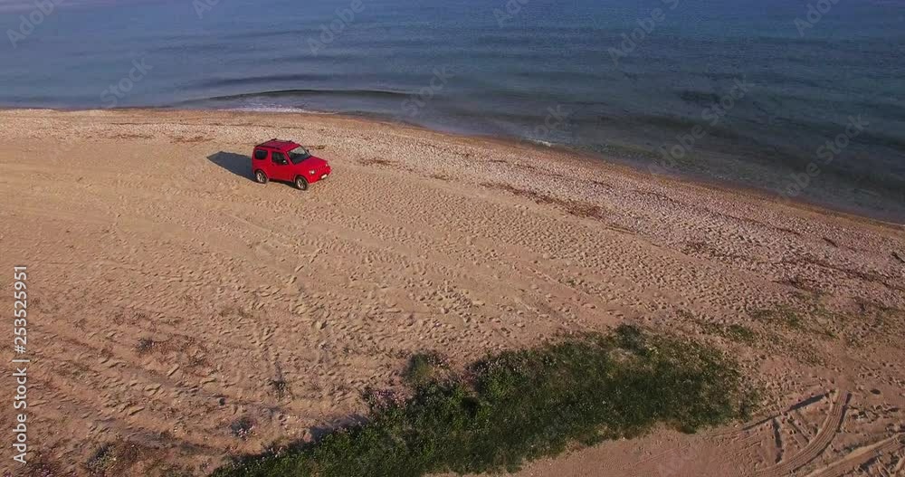 Aerial View car driving on the beach in greece surrounded by blue water Aerial View car driving on the beach in greece surrounded by blue water
