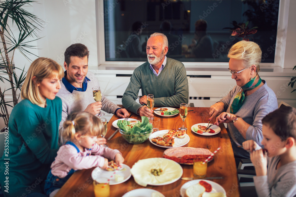 Multi generation family enjoying meal around table at home Multi generation family enjoying meal around table at home