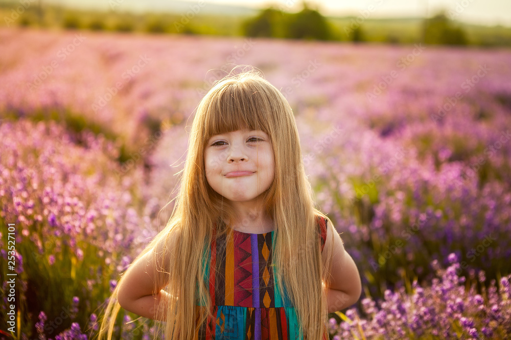 happy childhood. Laughing girl builds faces, dabbles. Barren child in a field of lavender at sunset. backlight Sun rays. happy childhood. Laughing girl builds faces, dabbles. Barren child in a field of lavender at sunset. backlight Sun rays.