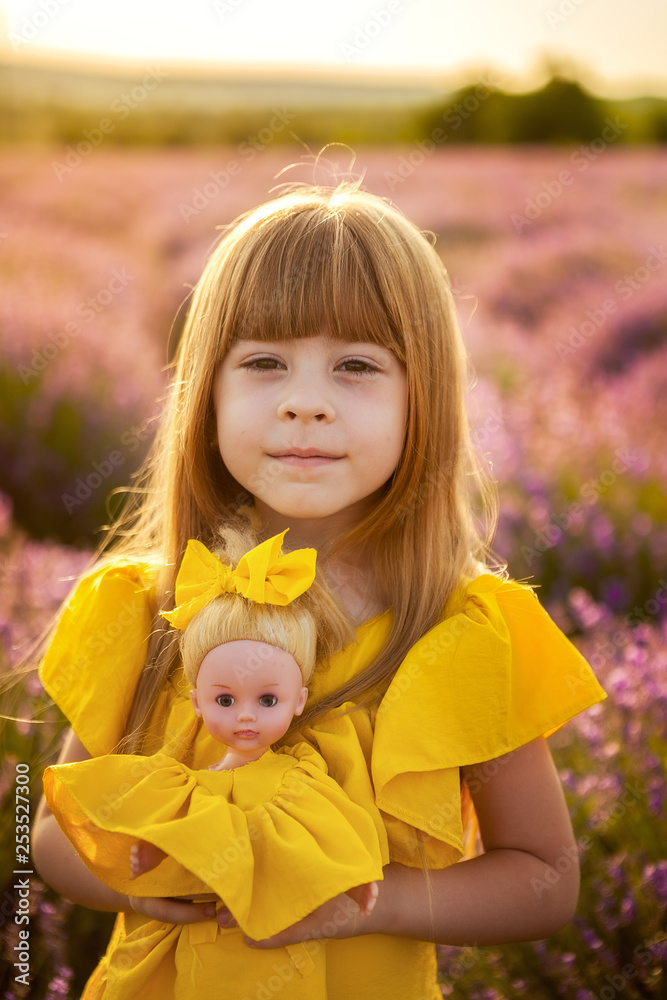 care for the younger ones. favorite toy. girl with a doll in her hands in the sunset light of a lavender field. care for the younger ones. favorite toy. girl with a doll in her hands in the sunset light of a lavender field.
