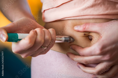 Woman making hormonal therapy injection into her belly. Close up syringe pen. Person in bedroom, in vitro fertilisation treatment. © Suzi Media 