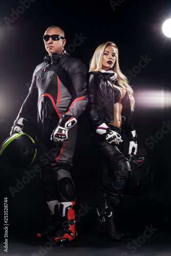 Fashion couple model DJ and biker with headphones and sunglasses, black leather jacket, leather pants, stylish pretty blonde woman and man in night casual outfit. Long wavy hairstyle.