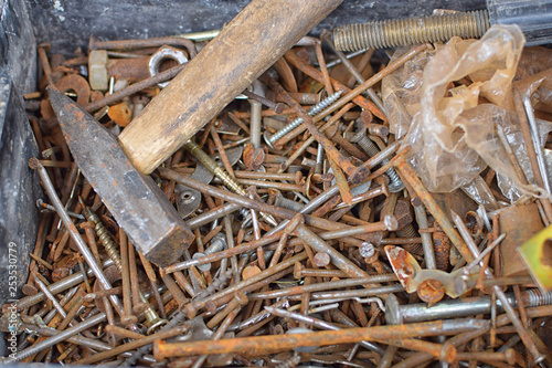 Heap of old rusty nails and screws on bottom of can with hummer