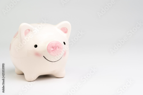 Smile pink piggy bank on white background with copy space using as happy saving and investment or positive economic and finance concept