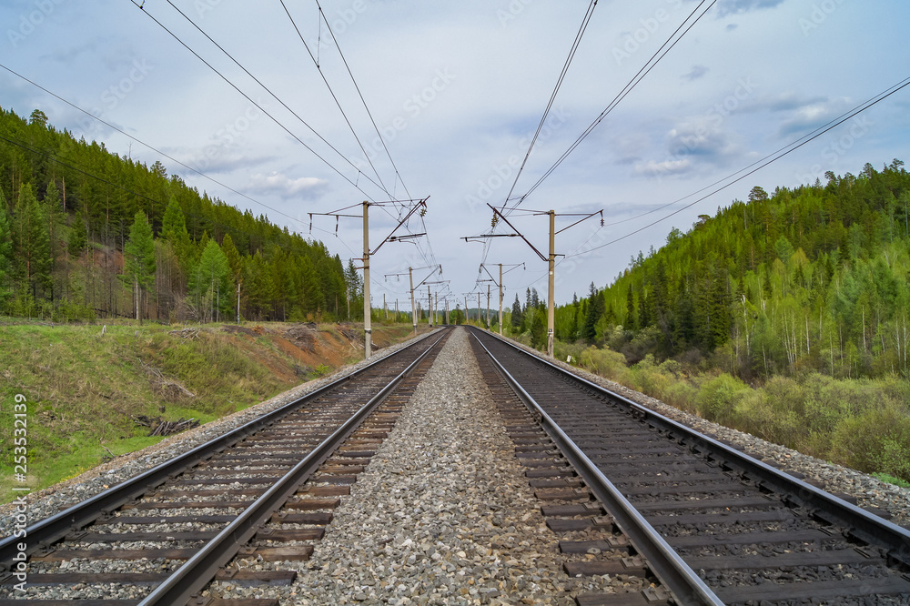 Railway tracks go into the distance. Railway on the background of green hills