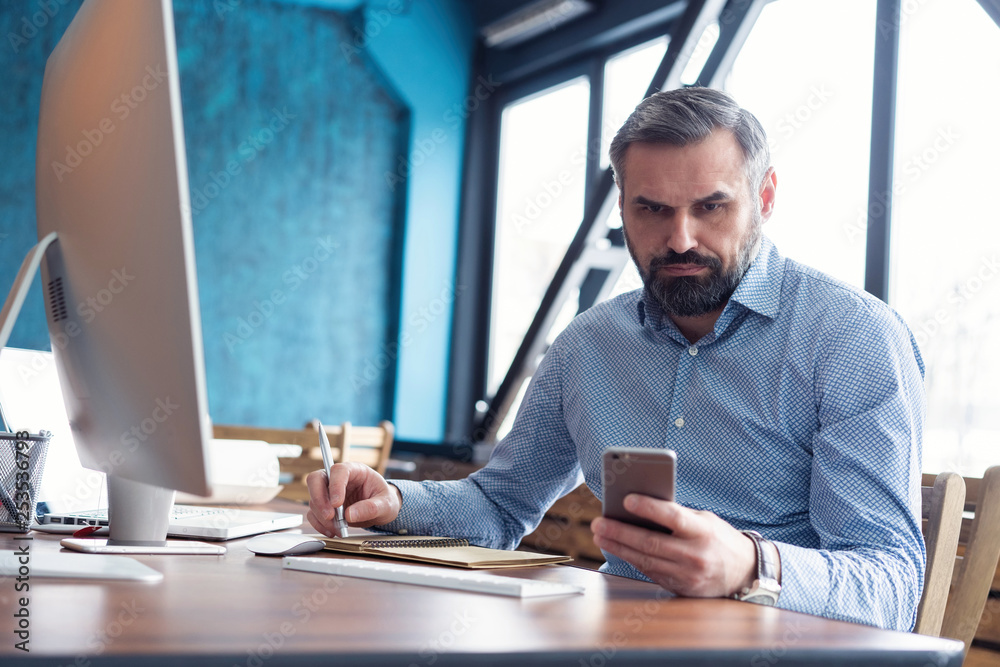 Obraz premium Mature businessman with smartphone in the office.