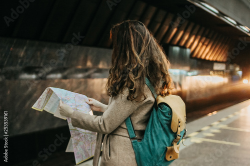 Young woman curly red head girl traveller with backpack and map in subway station in front of train