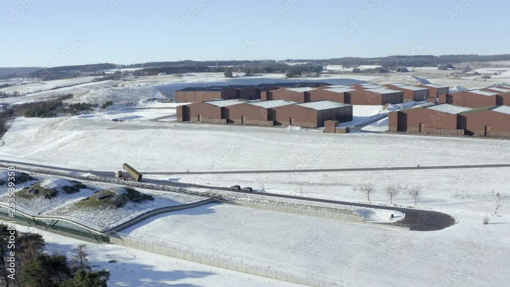 Aerial view of the Macallan whisky distillery surrounded by snow on a sunny winters day, Moray, Scotland - tracking right to left