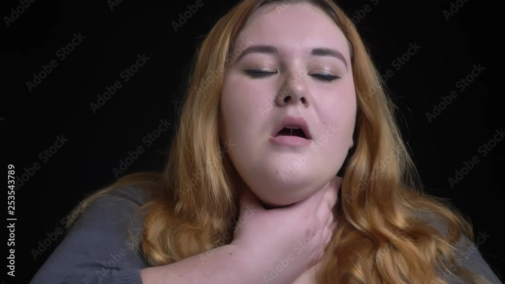 Closeup shoot of young overweight caucasian female having a sick throat and being ill in front of the camera Closeup shoot of young overweight caucasian female having a sick throat and being ill in front of the camera
