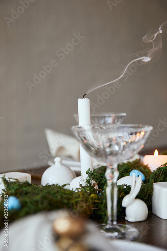 selective focus of candles, crystal glass and decorative bunnie on wooden table at home photo