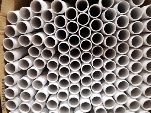 Stack of new white plastic pipes with selective focus top view. Drainage or water tube. Circle abstract background. Building material for pipeline 
