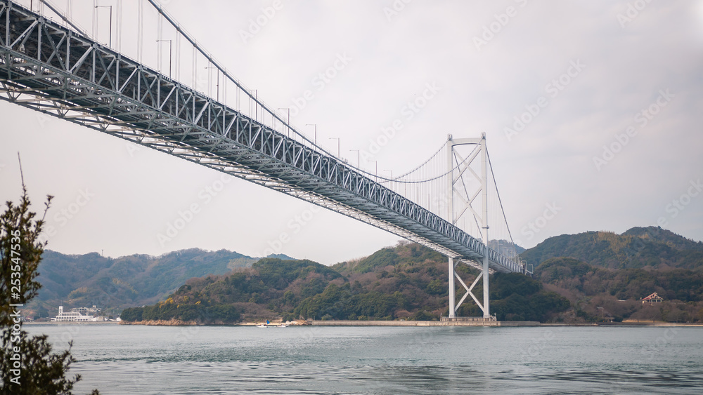 Obraz premium Landscape photo of the first bridge on the Shimanami Kaido cycling route going from Onomichi which connects Mukoujima Island and Innoshima Island in the Shikoku Region of Japan.