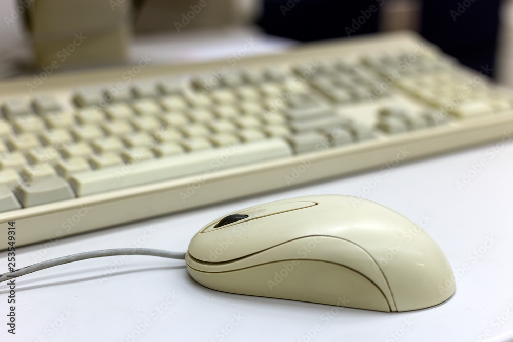 Close-up of white computer mouse on blurred PC keyboard background. Modern technology, information and communication concept. Close-up of white computer mouse on blurred PC keyboard background. Modern technology, information and communication concept.