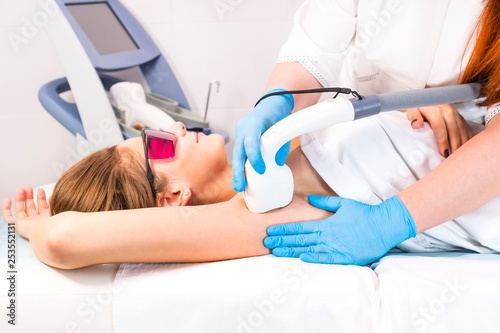 The process of laser depilation of female limbs in the beauty salon. 