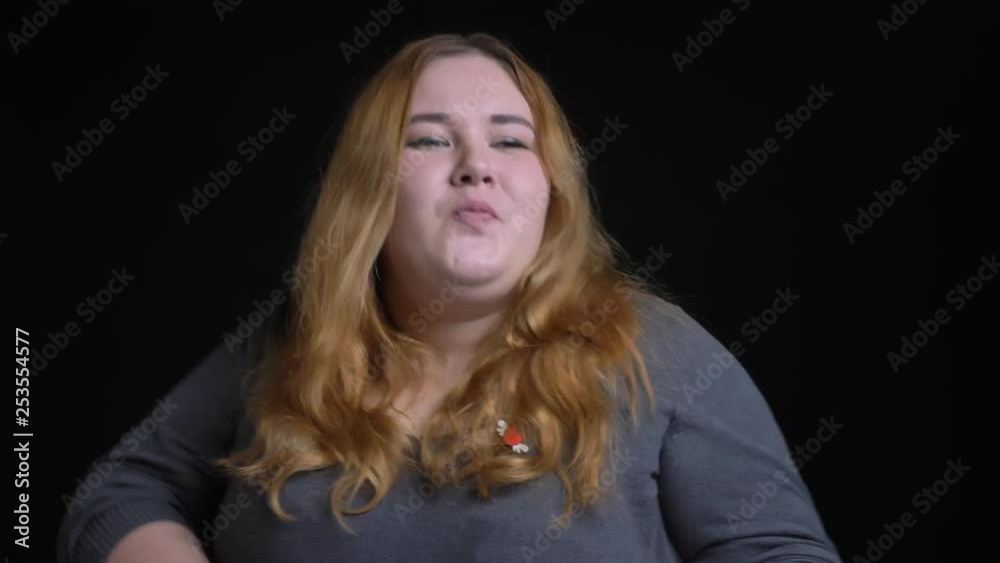 Closeup shoot of young overweight caucasian female with golden brunette hair dancing cheerfully and smiling in front of the camera Closeup shoot of young overweight caucasian female with golden brunette hair dancing cheerfully and smiling in front of the camera