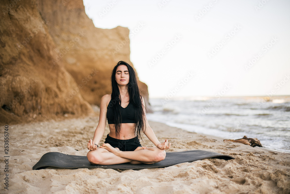 sport and lifestyle concept - woman doing sports by sea. Beautiful teenage sport woman doing stretching exercise on sand beach