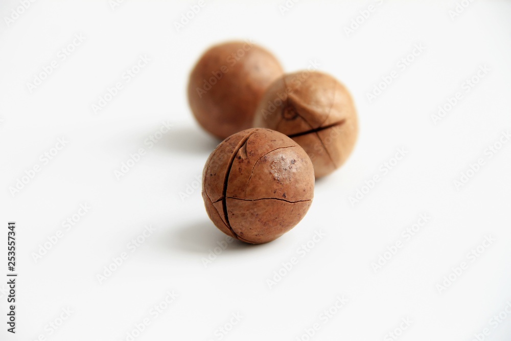 Three macadamia nuts on a white background the shell is cracked lined with a triangle Three macadamia nuts on a white background the shell is cracked lined with a triangle