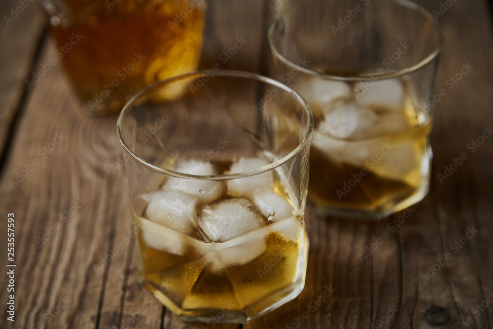 Whiskey with ice in glasses, rustic wood background, copy space Whiskey with ice in glasses, rustic wood background, copy space