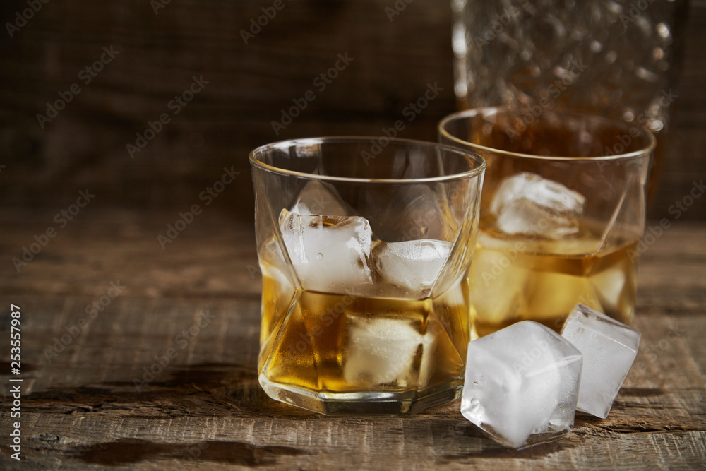 Whiskey with ice in glasses, rustic wood background, copy space Whiskey with ice in glasses, rustic wood background, copy space