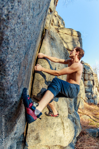 Fototapeta Naklejka Na Ścianę i Meble -  rrock shoe close-up of a rock climber climbs a boulder over a rock without insurance