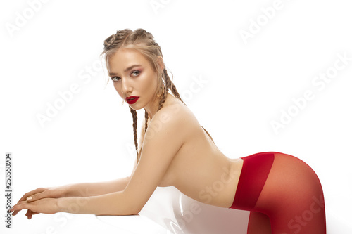 Sexy nude blonde girl in red tights lying on white chair