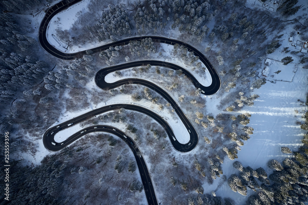 Aerial drone view of a serpentine in Predeal mountain road whit forest covered in snow on winter season, Predeal, Romania