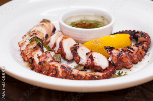 grilled squid rings on a wooden board with sauce