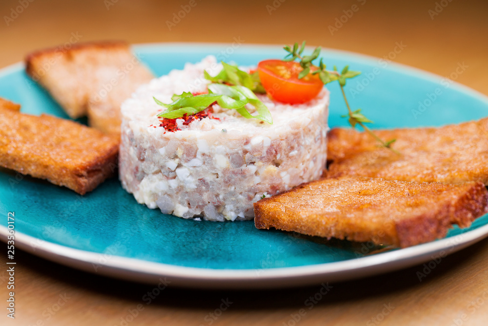 Meat salad with toasted black bread croutons on a blue plate