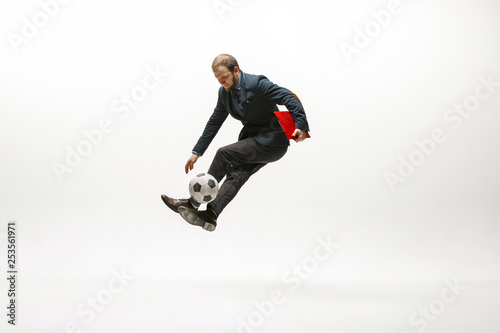 Businessman with clipboard and football ball in office. Soccer freestyle. Concept of balance and agility in business. Manager perfoming tricks isolated on white studio background.