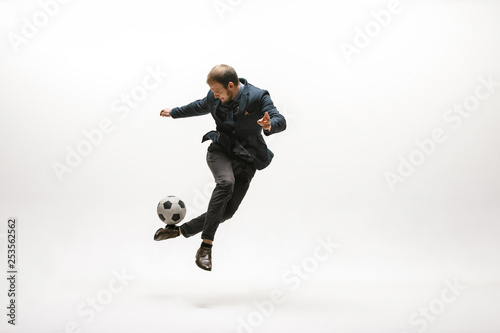 Businessman with football ball in office. Soccer freestyle. Concept of balance and agility in business. Manager perfoming tricks isolated on white studio background. photo