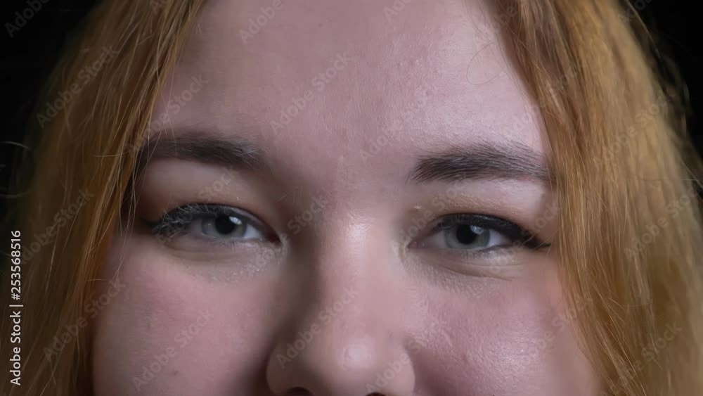 Closeup shoot of young attractive overweight female face with gray eyes looking straight at camera with smiling facial expression Closeup shoot of young attractive overweight female face with gray eyes looking straight at camera with smiling facial expression
