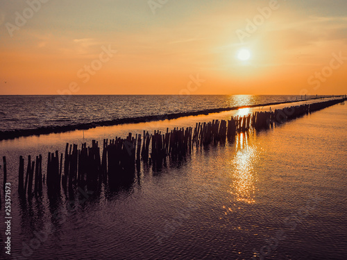 Golden natural sea sunset view at horizon with silhouette and orange sky landscape. Sunset or sunrise reflection in nature with sun in clouds above black sea scenery Bangkhuntien Bangkok Thailand