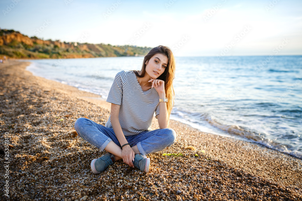 Young beautiful pretty girl sitting at sandy beach.