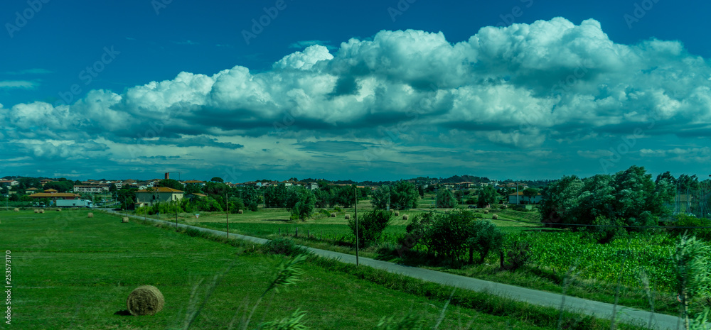 Italy,Florence to Pisa Train, a large green field with clouds in the sky