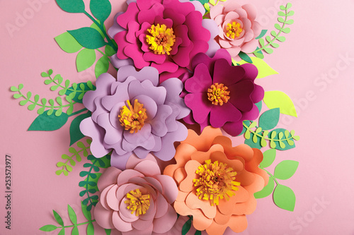 top view of paper flowers, green and yellow leaves on pink background © LIGHTFIELD STUDIOS