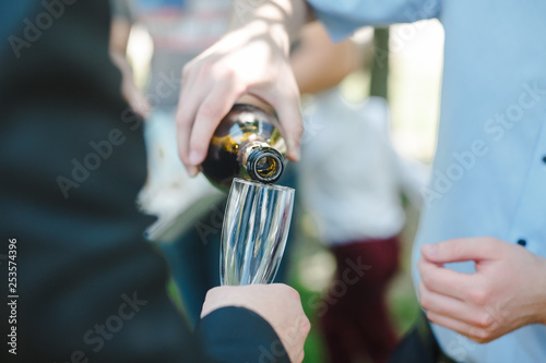 Man serving champagne to friends sitting around table during party.
