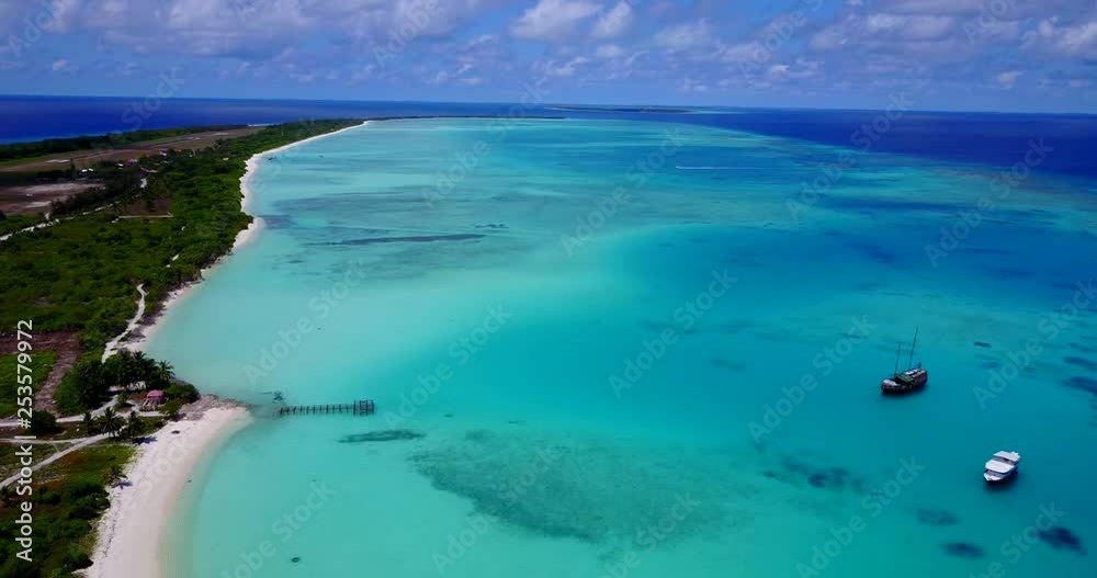 Gentle rise above calm waters alongside Maldives coast and white beach. Vast blue skies and a few boats in the crystal clear ocean. Tranquil scenery. Gentle rise above calm waters alongside Maldives coast and white beach. Vast blue skies and a few boats in the crystal clear ocean. Tranquil scenery.