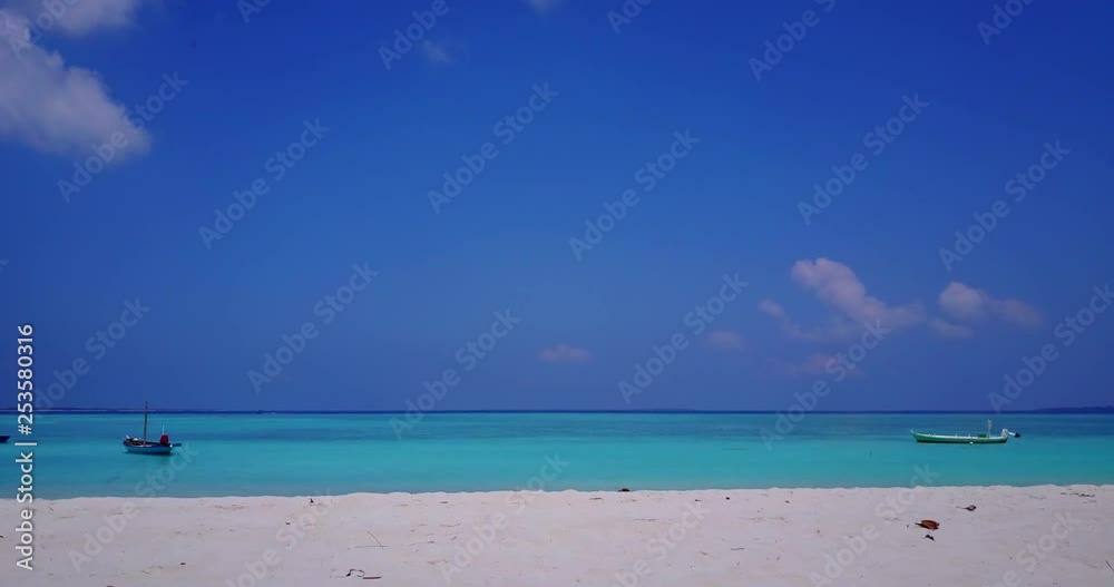 Galapagos island. Soft aerial just above white tropical beach towards crystal clear ocean. Boats lingering in shallow turquoise waters. Galapagos island. Soft aerial just above white tropical beach towards crystal clear ocean. Boats lingering in shallow turquoise waters.