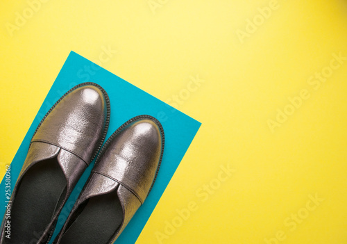 Pair of sparkly female shoes on yellow and blue background with copyspace. Flat lay style.