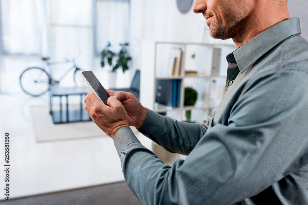 cropped view of businessman using smartphone in modern office cropped view of businessman using smartphone in modern office