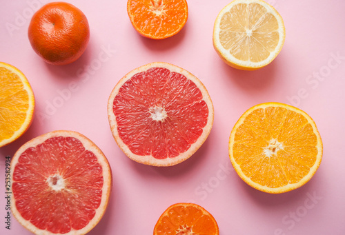 Flat lay of cut ripe juicy grapefruit  lemon and orange on pink background. Flat lay style.