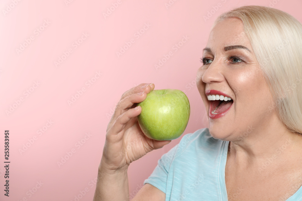 Smiling woman with perfect teeth and green apple on color background. Space for text Smiling woman with perfect teeth and green apple on color background. Space for text