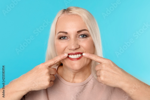 Woman showing perfect teeth on color background