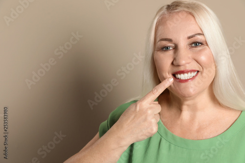 Smiling woman with perfect teeth on color background. Space for text