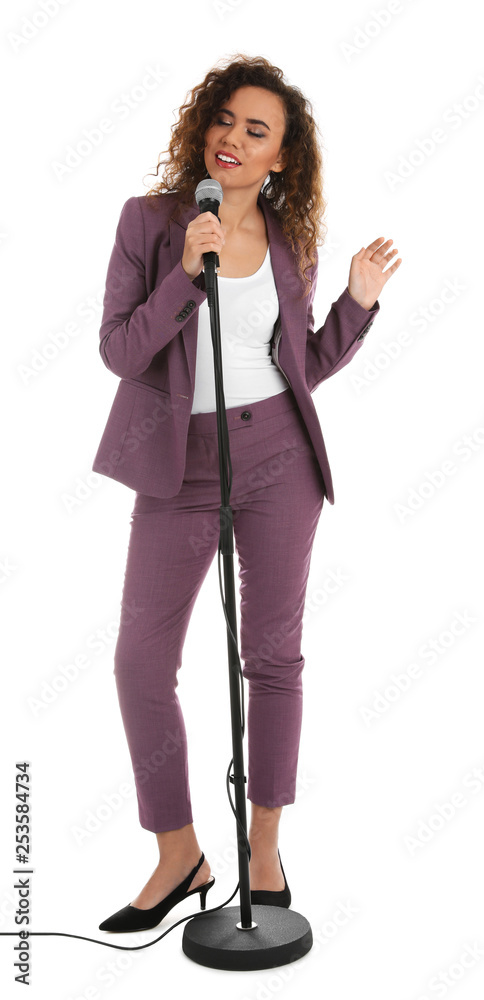 Fototapeta premium Curly African-American woman in suit posing with microphone on white background